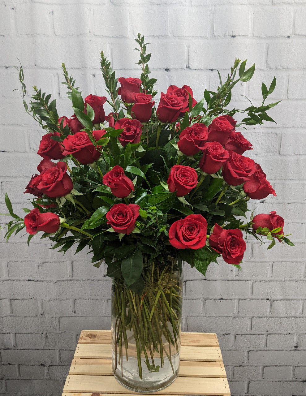 Red roses in a vase with greenery, kept fresh in Dubai's heat
